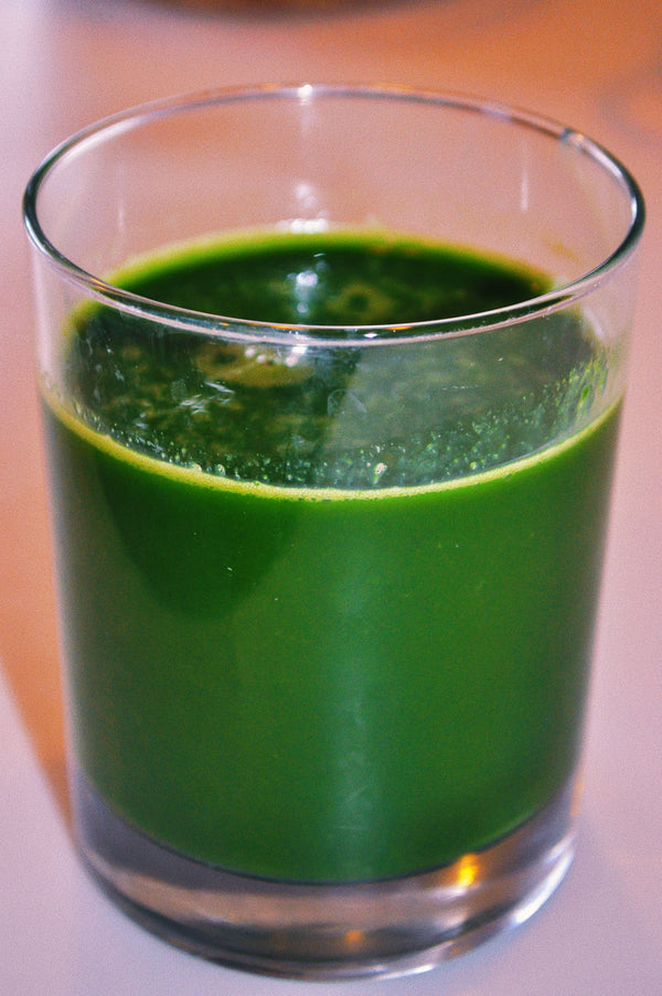 A green celery juice liquid in a transparent glass