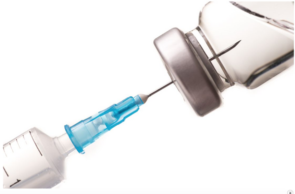 A syringe taking a dose of medicine in a vial